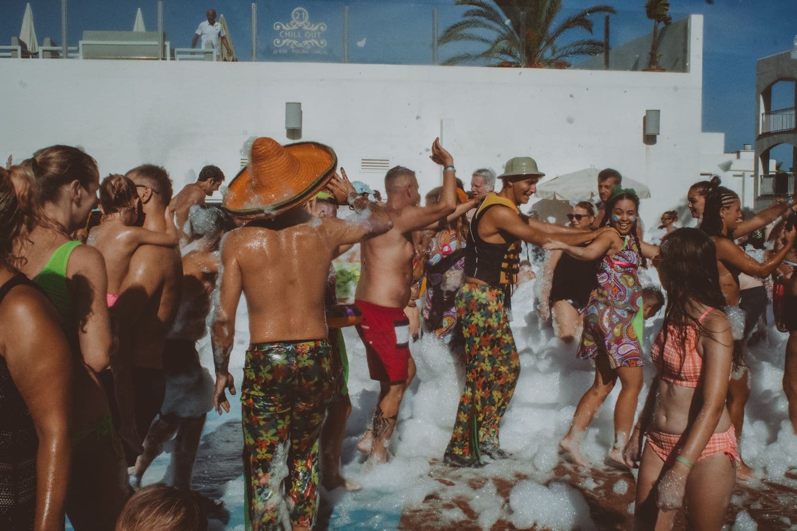 Solrikt skumparty ved bassenget med dansende gjester