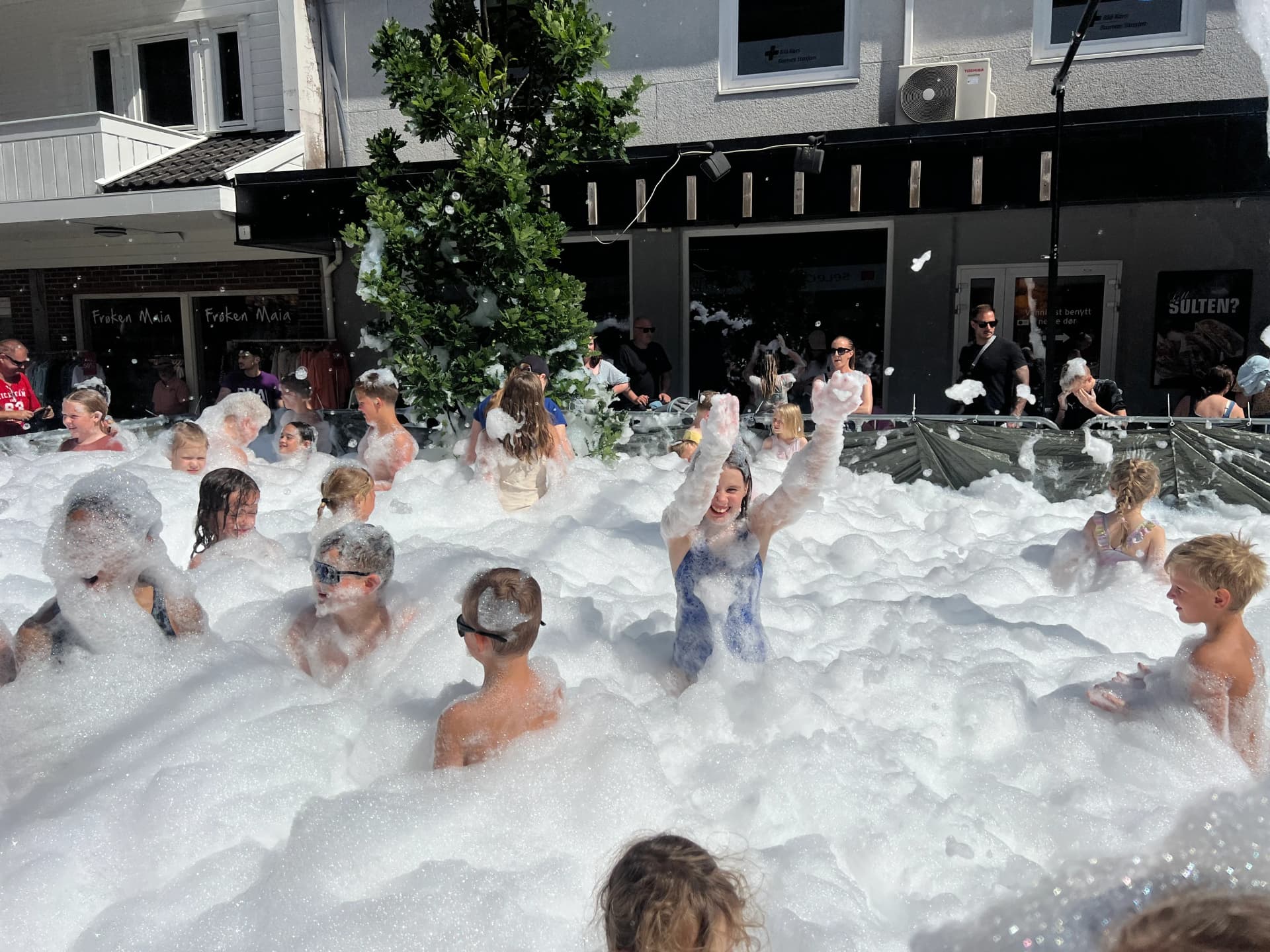 Full skumbinge med lekende barn på torgfest
